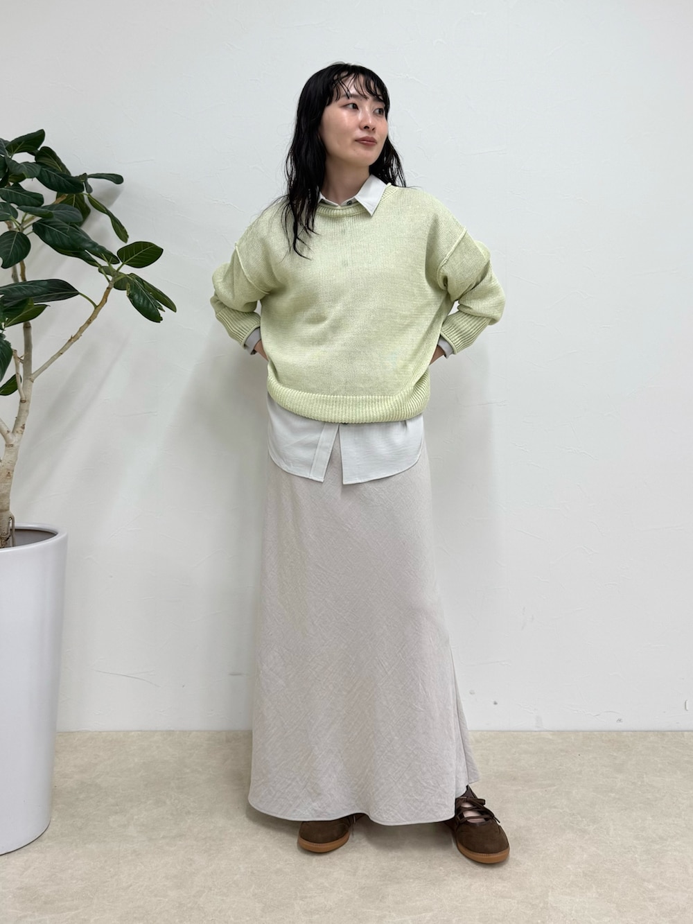 グレー系のシャツ/ブラウス、グリーン系のニット/セーター、ベージュ系のスカートを着用したレディースの春コーディネートの2枚目の写真