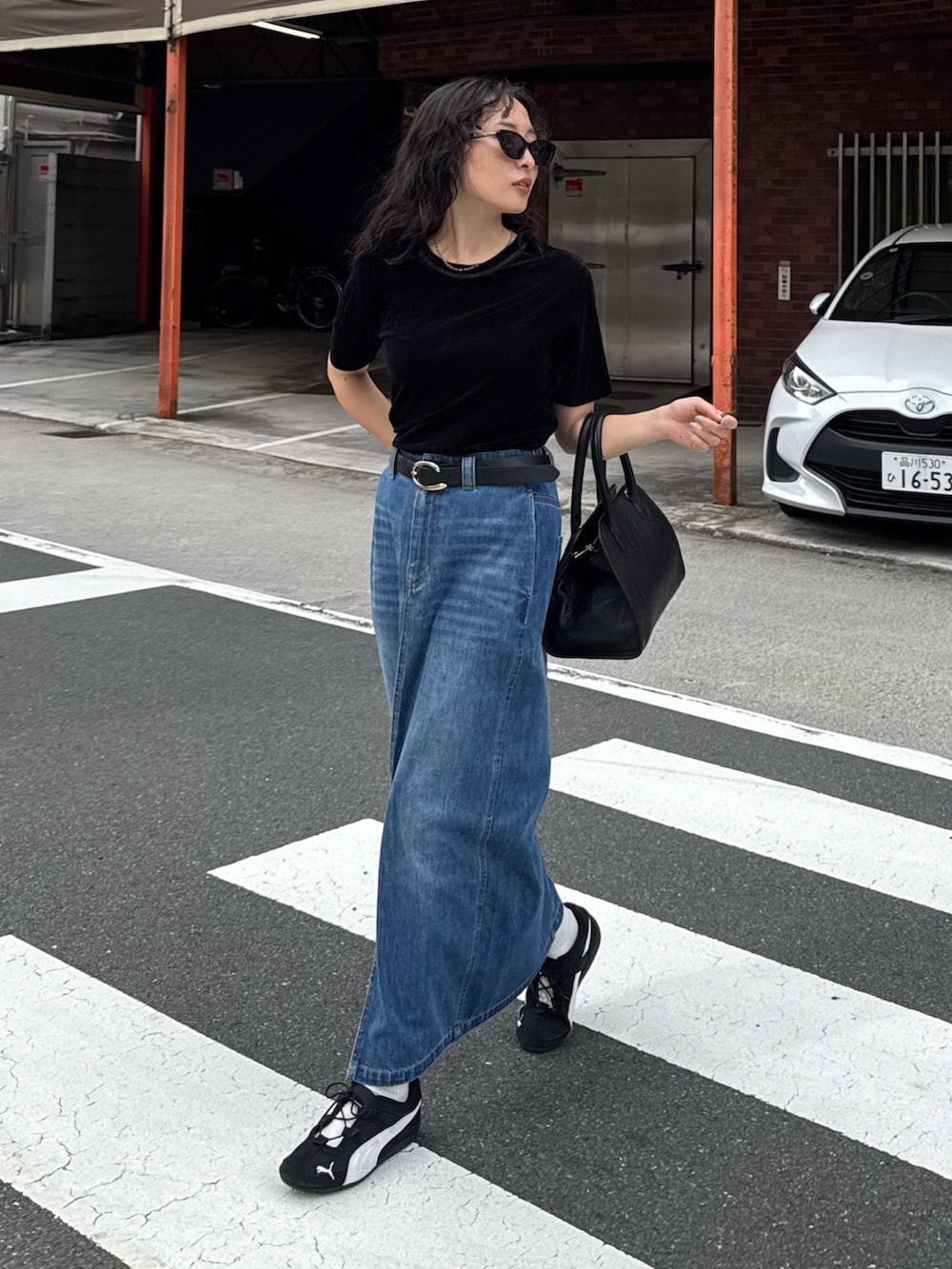 ブラック系のTシャツ/カットソー、ブルー系のデニムスカート、ブラック系のショルダーバッグを着用したレディースの夏コーディネートの2枚目の写真