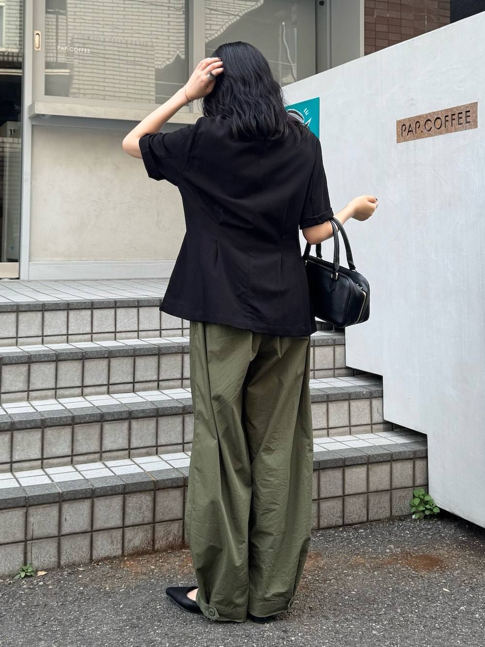 ブラック系のテーラードジャケット、グリーン系のその他パンツ、ブラック系のショルダーバッグを着用したレディースの春コーディネートの4枚目の写真