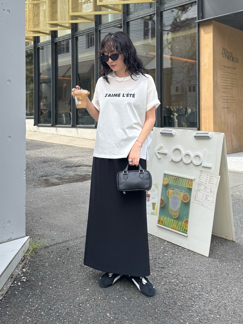 ホワイト系のTシャツ/カットソー、ブラック系のスカート、ブラック系のショルダーバッグを着用したレディースの夏コーディネートの6枚目の写真