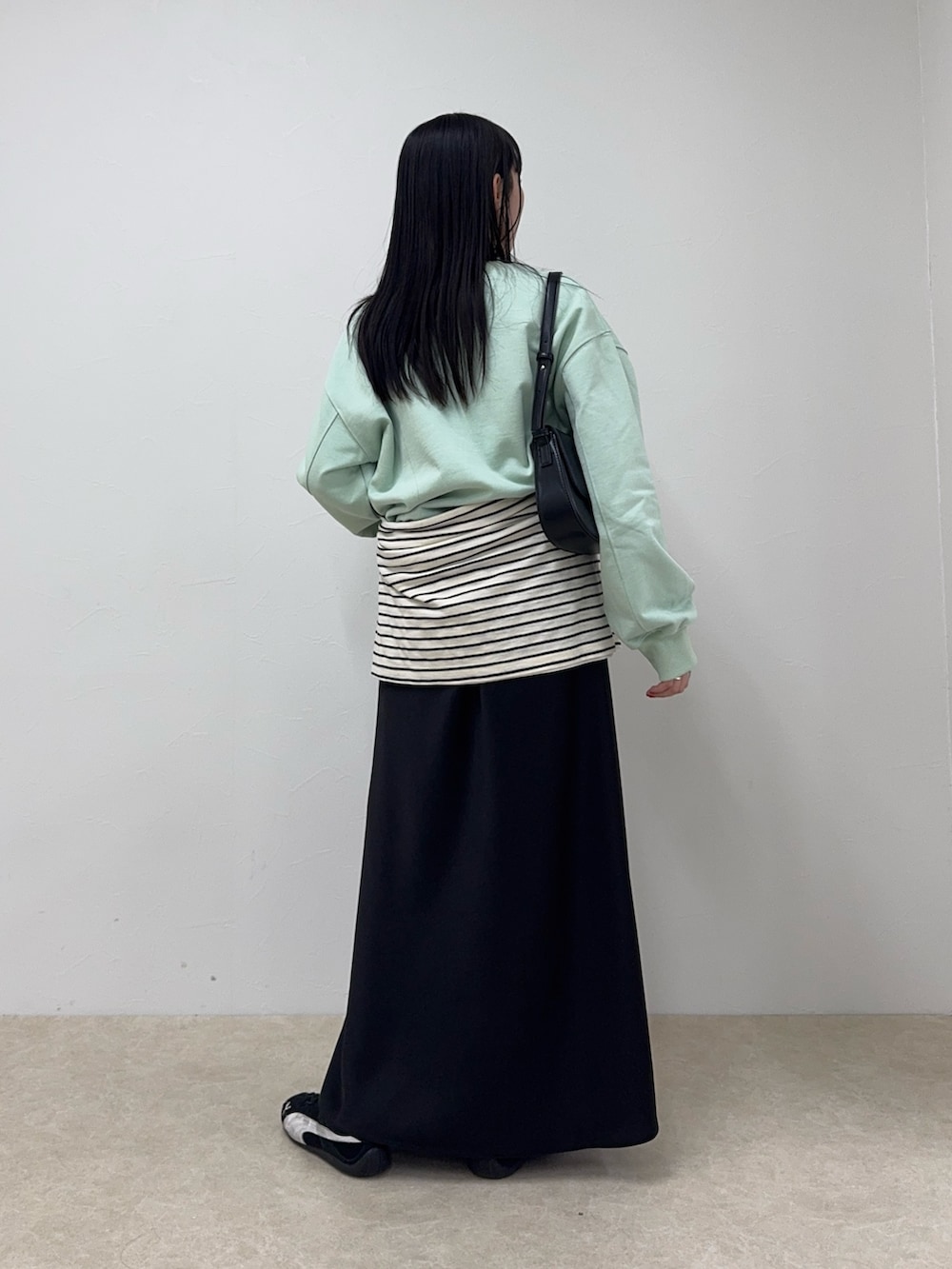 グリーン系のスウェット、ブラック系のスカート、ホワイト系のTシャツ/カットソーを着用したレディースの冬コーディネートの3枚目の写真