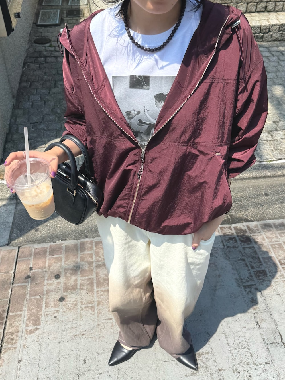 レッド系のブルゾン、ホワイト系のTシャツ/カットソー、ブラウン系のデニムパンツを着用したレディースの秋コーディネートの3枚目の写真