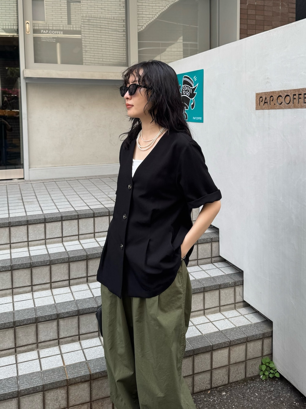 ブラック系のテーラードジャケット、グリーン系のその他パンツ、ブラック系のショルダーバッグを着用したレディースの春コーディネートの3枚目の写真