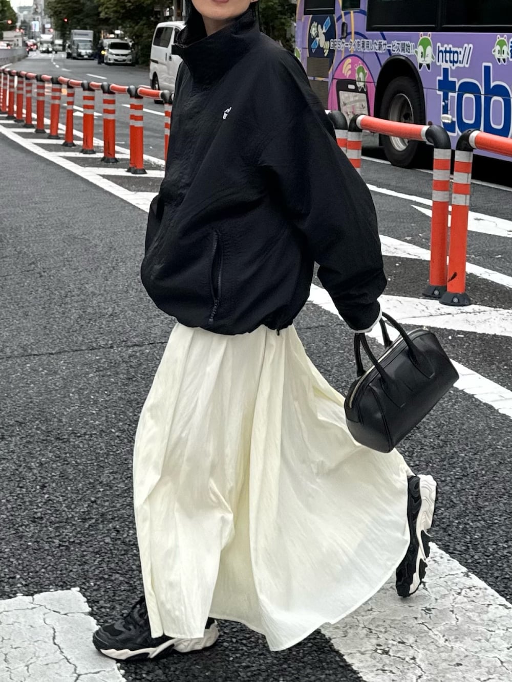 ホワイト系のスカート、グレー系のスウェット、ブラック系のマウンテンパーカーを着用したレディースの秋コーディネートの5枚目の写真