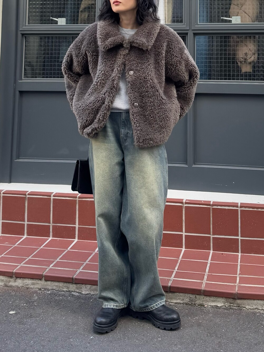 グレー系のムートンコート、グレー系のニット/セーター、ブラック系のハンドバッグを着用したレディースの冬コーディネートの5枚目の写真