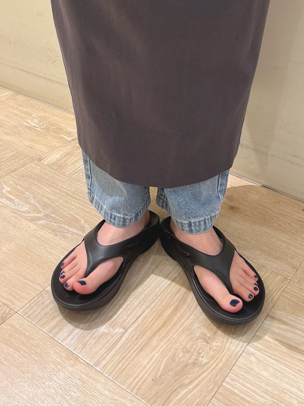 グレー系のワンピース、ブルー系のデニムパンツ、ブラック系のサンダルを着用したレディースの春コーディネートの3枚目の写真