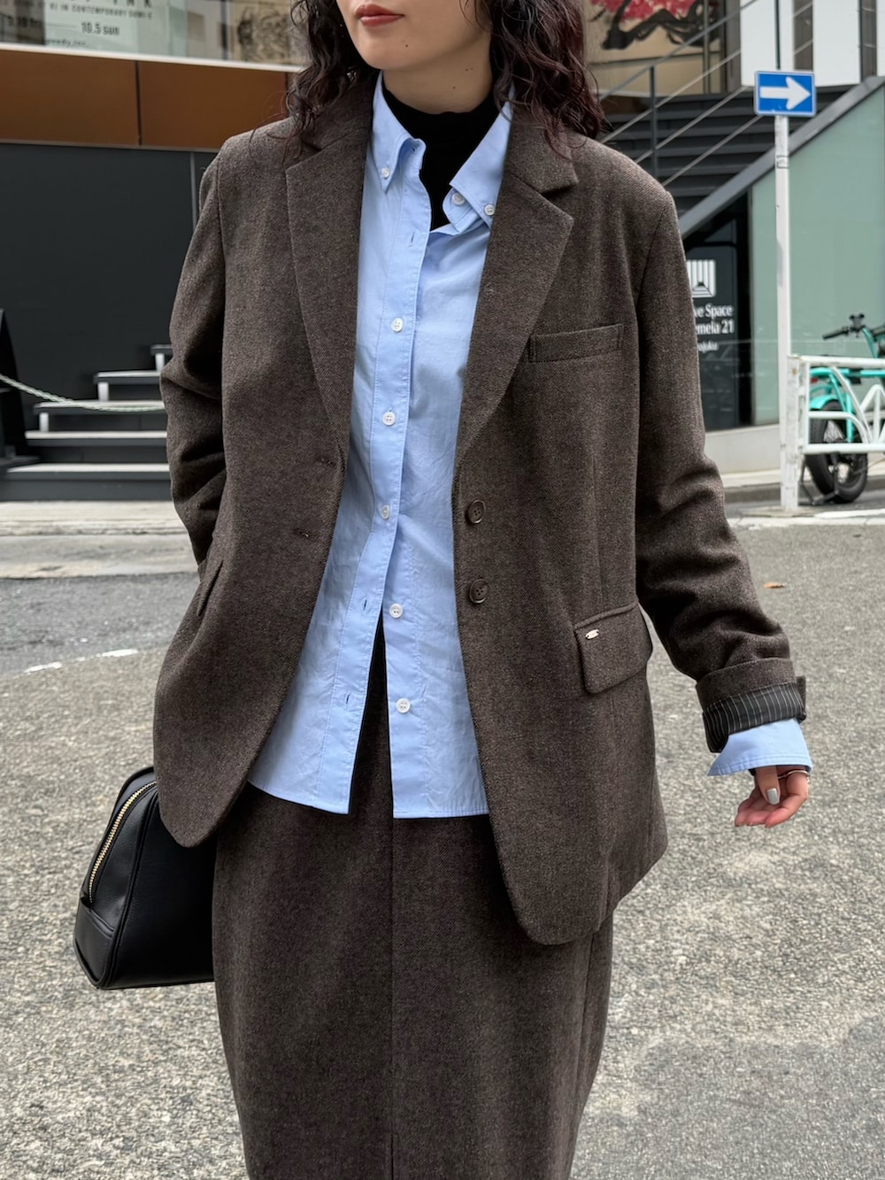 ブラウン系のテーラードジャケット、ブルー系のシャツ/ブラウス、ブラウン系のスカートを着用したレディースの秋コーディネートの6枚目の写真
