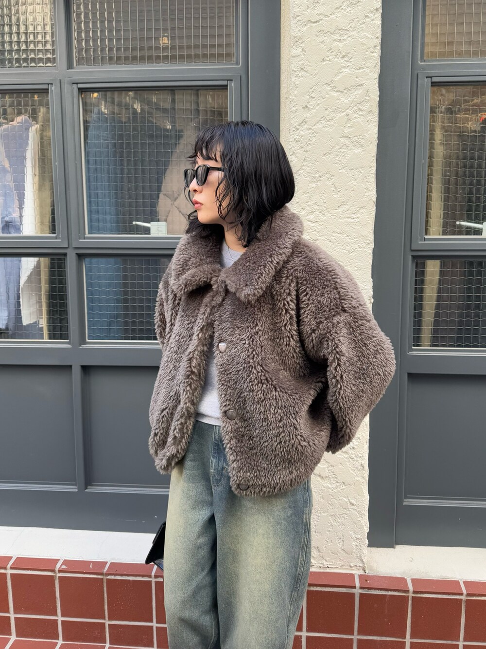 グレー系のムートンコート、グレー系のニット/セーター、ブラック系のハンドバッグを着用したレディースの冬コーディネートの4枚目の写真
