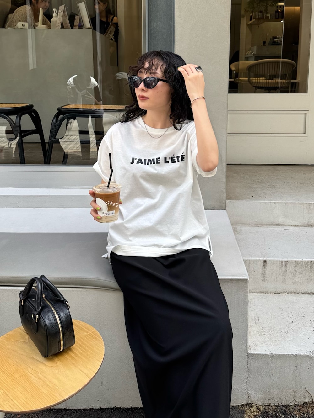 ホワイト系のTシャツ/カットソー、ブラック系のスカート、ブラック系のショルダーバッグを着用したレディースの夏コーディネートの4枚目の写真