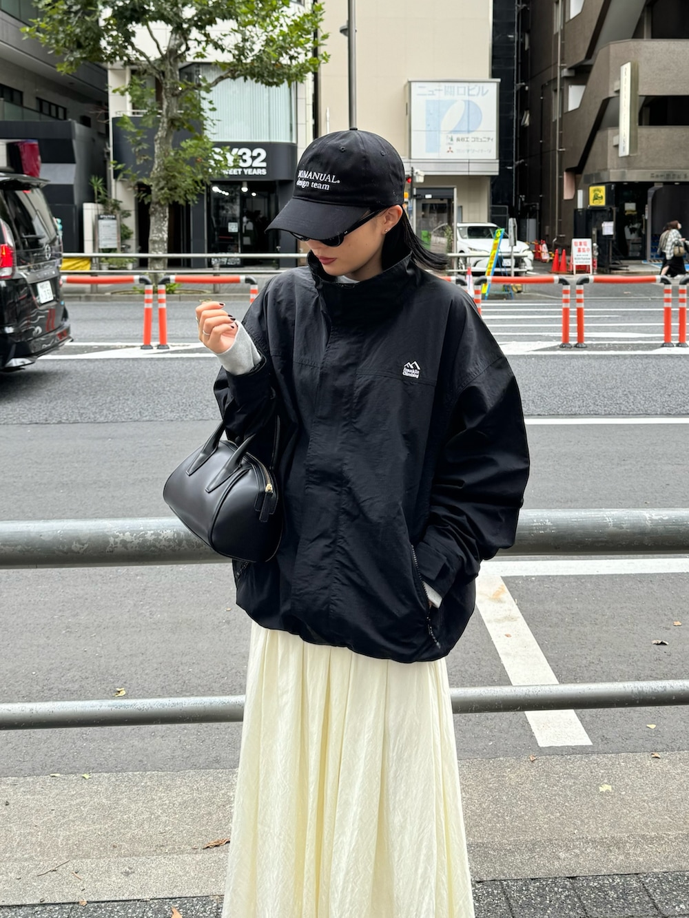 ホワイト系のスカート、グレー系のスウェット、ブラック系のマウンテンパーカーを着用したレディースの秋コーディネートの2枚目の写真