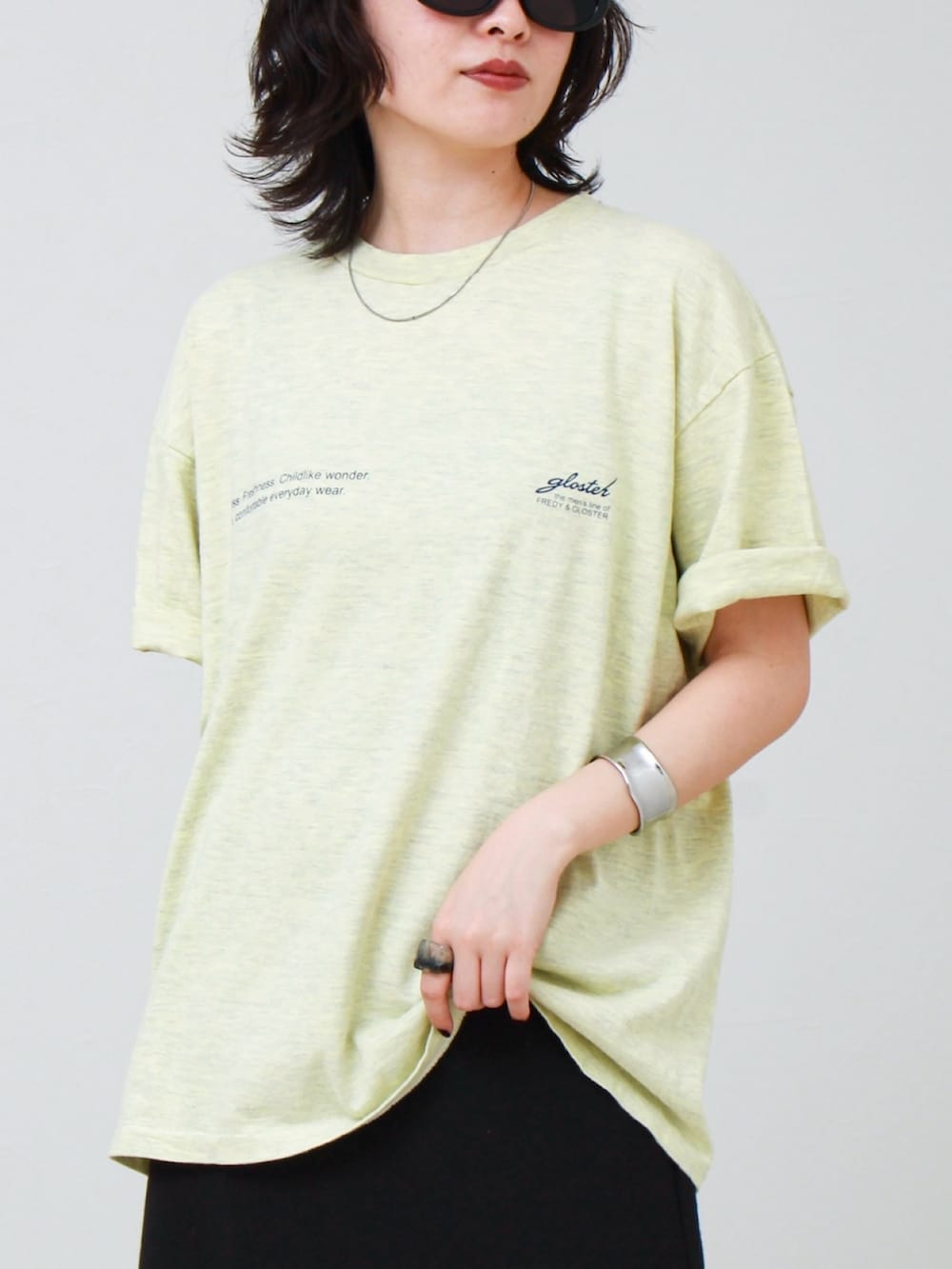 イエロー系のTシャツ/カットソー、ブラック系のスカート、ブラック系のサンダルを着用したレディースの夏コーディネートの4枚目の写真
