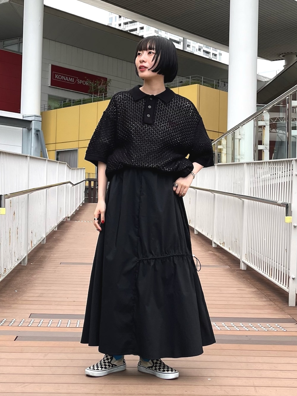 ブラック系のポロシャツ、ホワイト系のTシャツ/カットソー、ブラック系のスカートを着用したレディースの春コーディネートの2枚目の写真