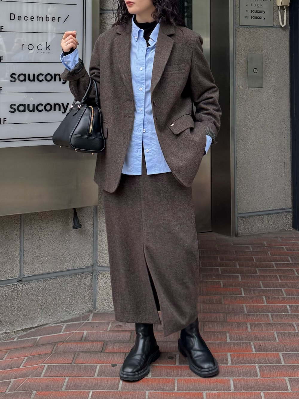 ブラウン系のテーラードジャケット、ブルー系のシャツ/ブラウス、ブラウン系のスカートを着用したレディースの秋コーディネートの2枚目の写真