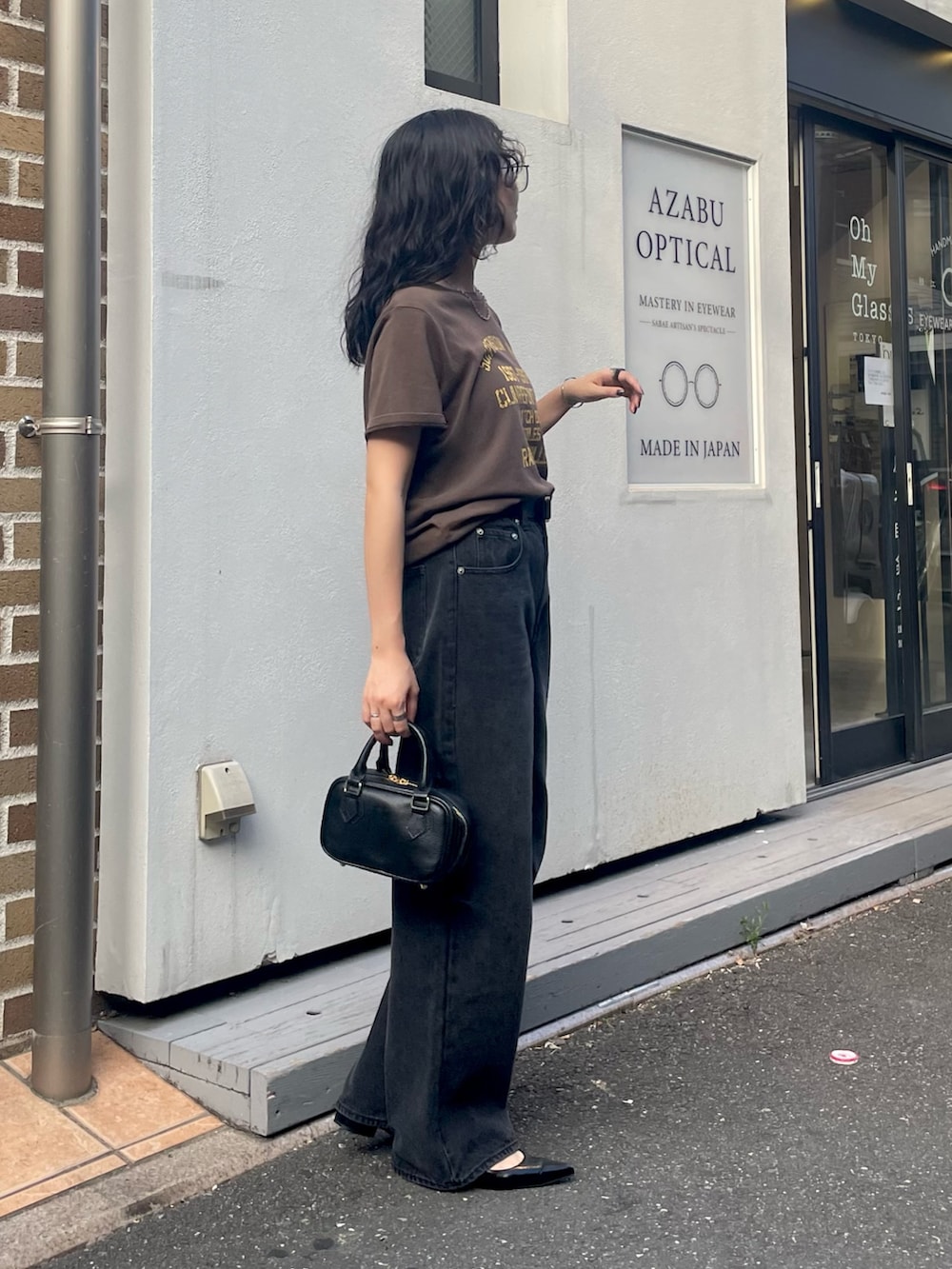 ブラウン系のTシャツ/カットソー、ブラック系のデニムパンツ、ブラック系のショルダーバッグを着用したレディースの夏コーディネートの4枚目の写真