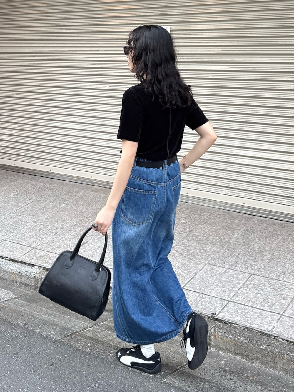 ブラック系のTシャツ/カットソー、ブルー系のデニムスカート、ブラック系のショルダーバッグを着用したレディースの夏コーディネートの5枚目の写真