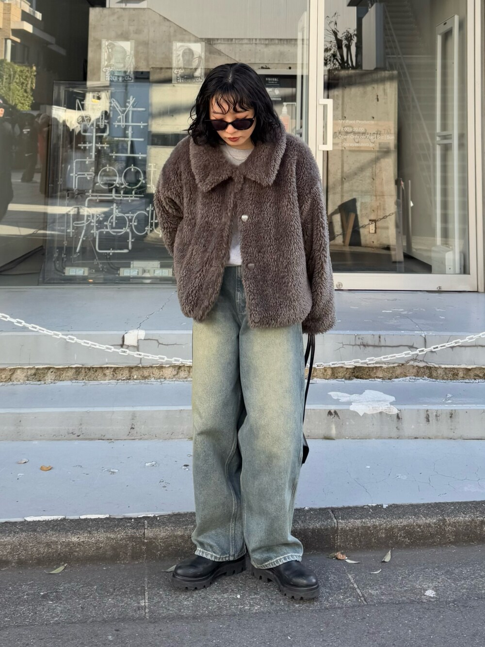 グレー系のムートンコート、グレー系のニット/セーター、ブラック系のハンドバッグを着用したレディースの冬コーディネートの2枚目の写真