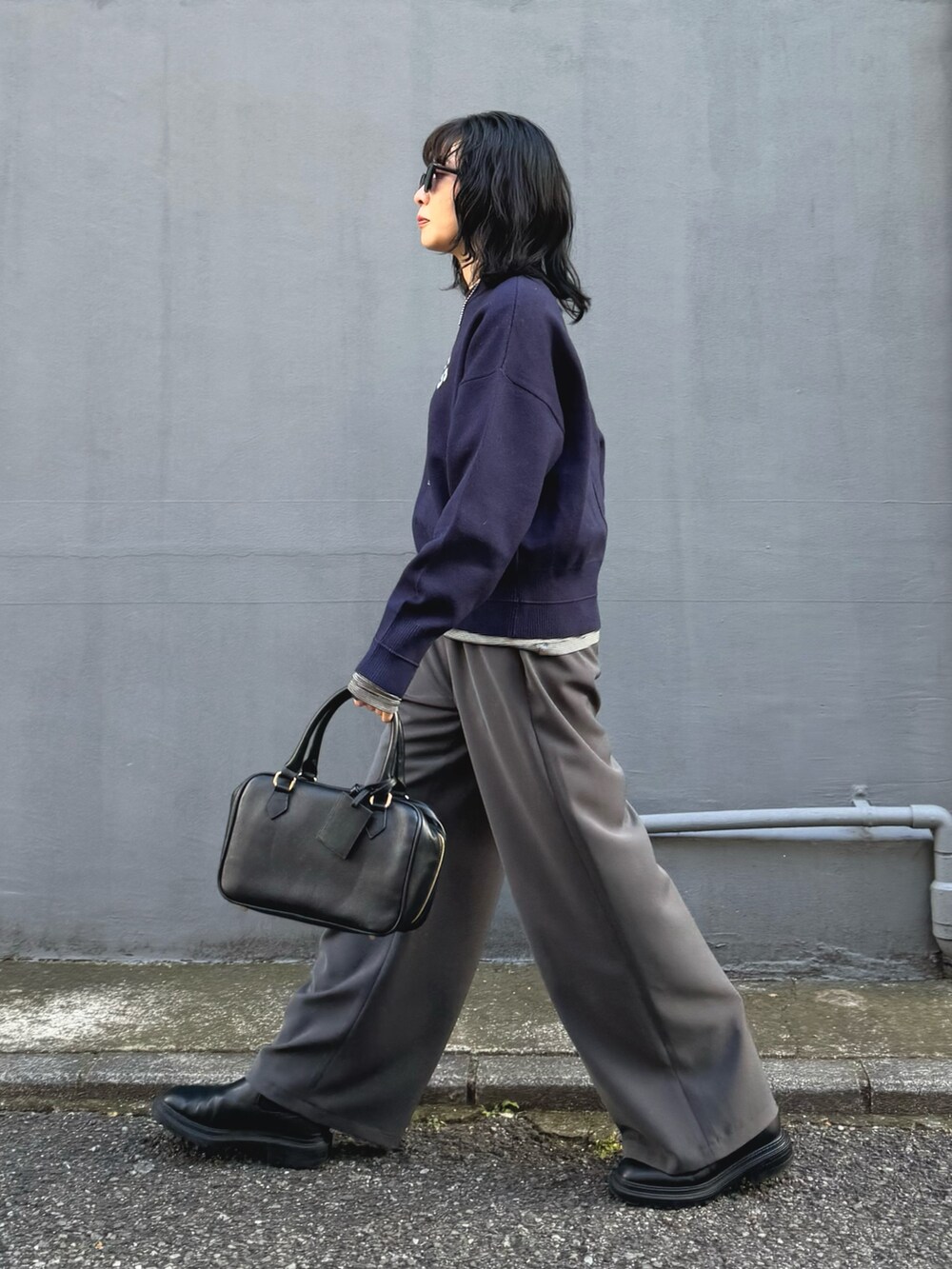 ブルー系のニット/セーター、グレー系のその他パンツ、ブラック系のハンドバッグを着用したレディースの冬コーディネートの2枚目の写真