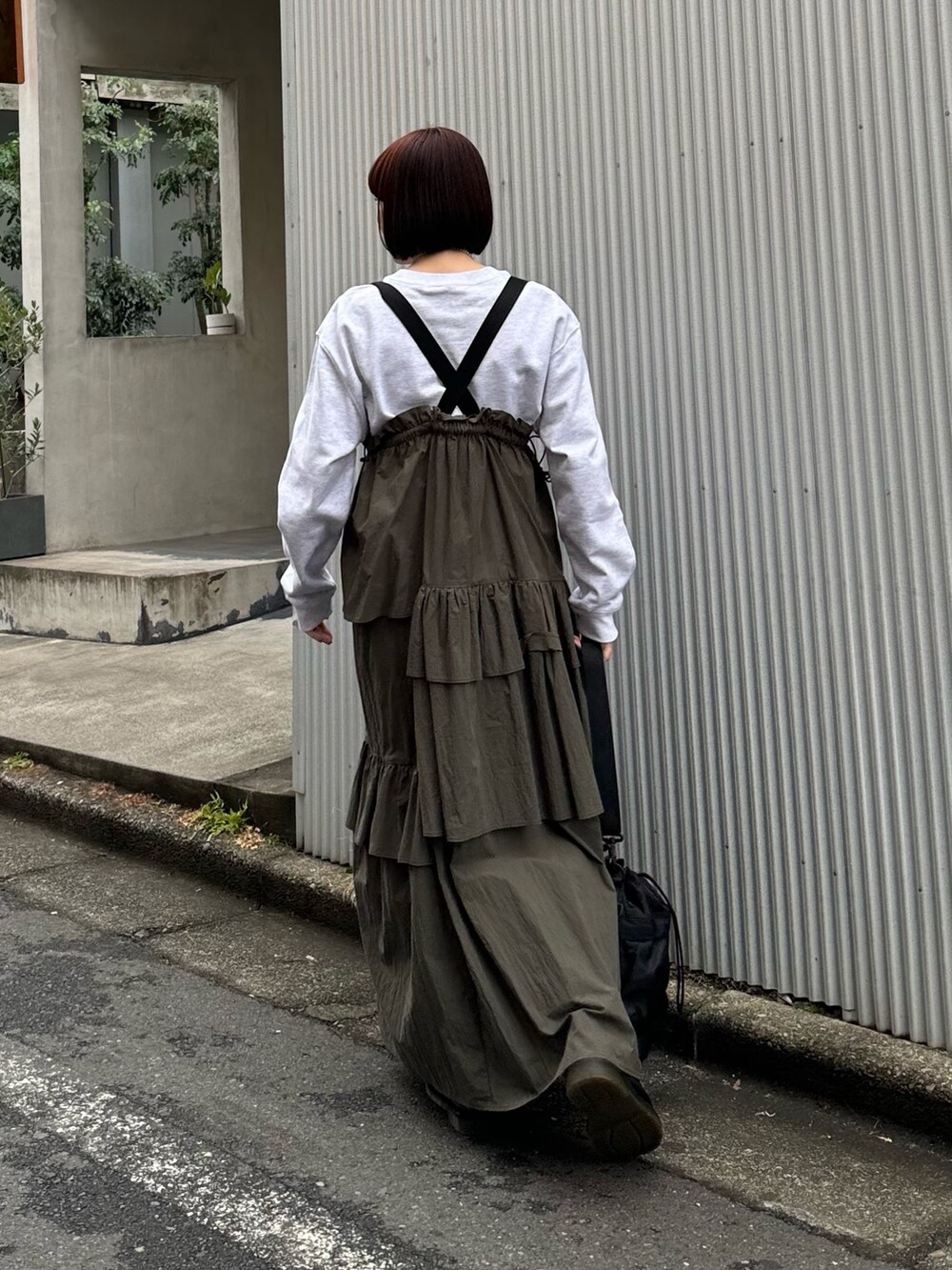 グレー系のスウェット、グリーン系のジャンパースカート、ブラック系のショルダーバッグを着用したレディースの冬コーディネートの6枚目の写真