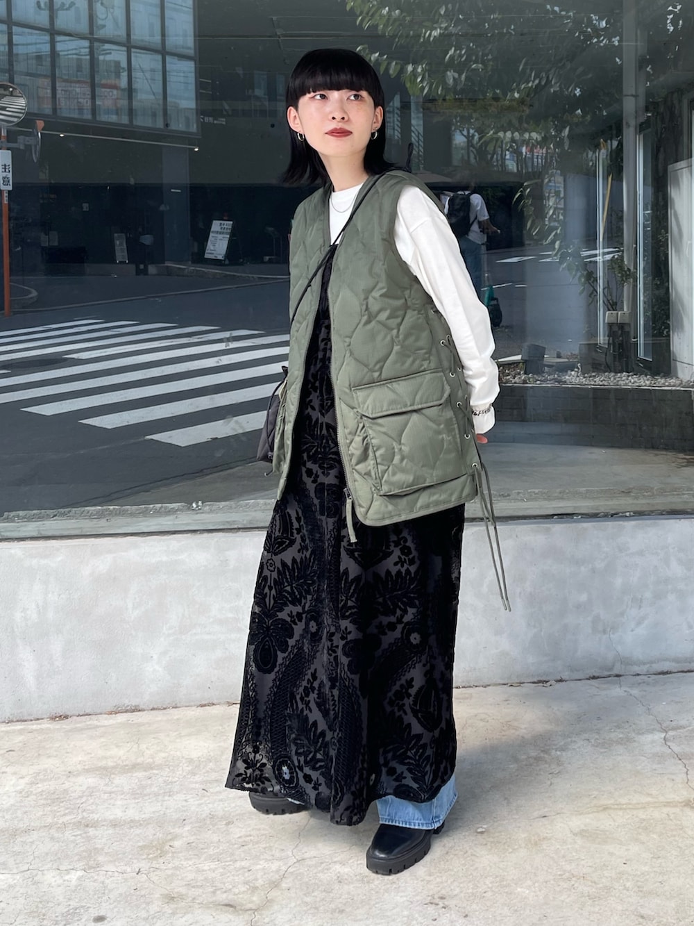 グリーン系のダウンベスト、ブラック系のワンピース、ブラック系のショルダーバッグを着用したレディースの秋コーディネートの2枚目の写真