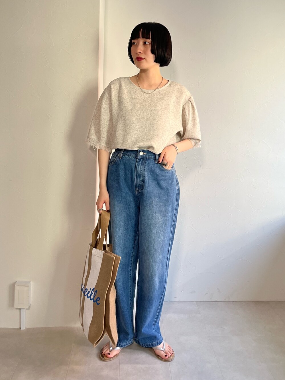 ホワイト系のシャツ/ブラウス、ブルー系のデニムパンツ、ベージュ系のバッグを着用したレディースの春コーディネートの2枚目の写真