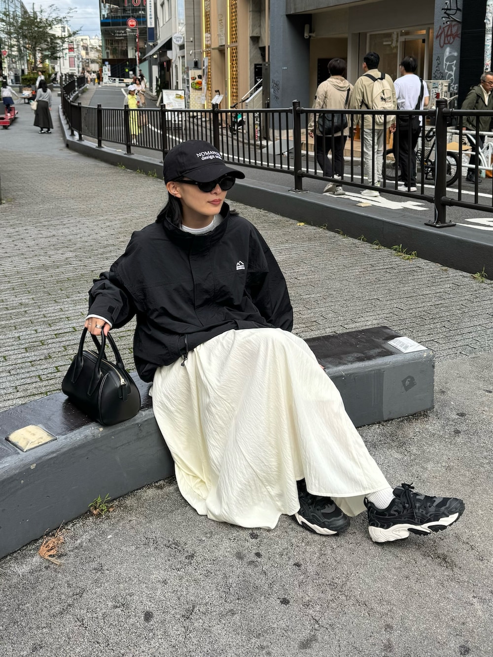 ホワイト系のスカート、グレー系のスウェット、ブラック系のマウンテンパーカーを着用したレディースの秋コーディネートの4枚目の写真