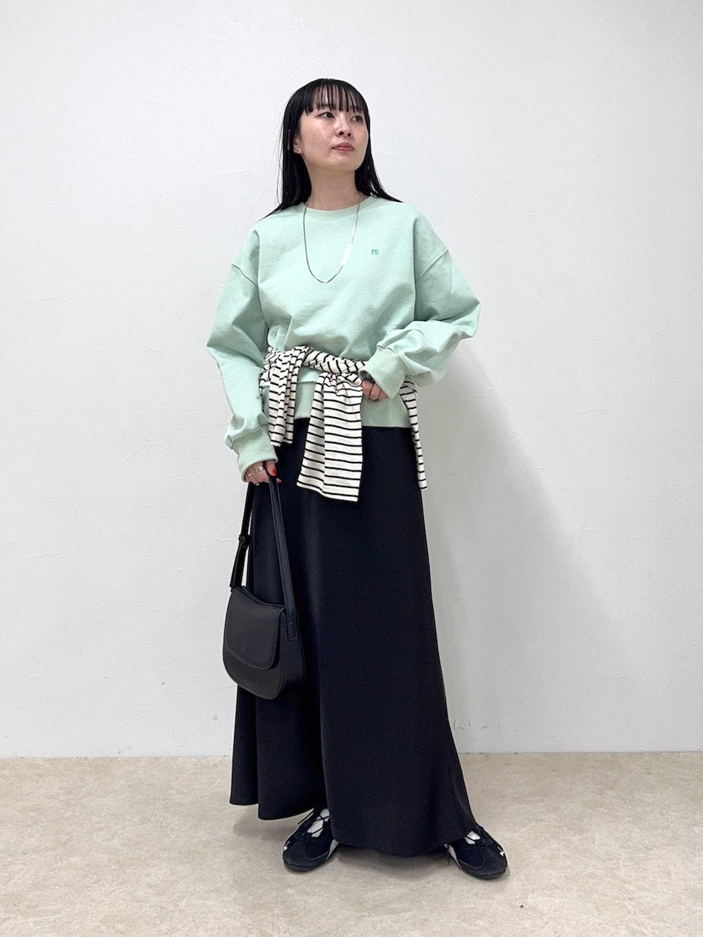 グリーン系のスウェット、ブラック系のスカート、ホワイト系のTシャツ/カットソーを着用したレディースの冬コーディネートの2枚目の写真