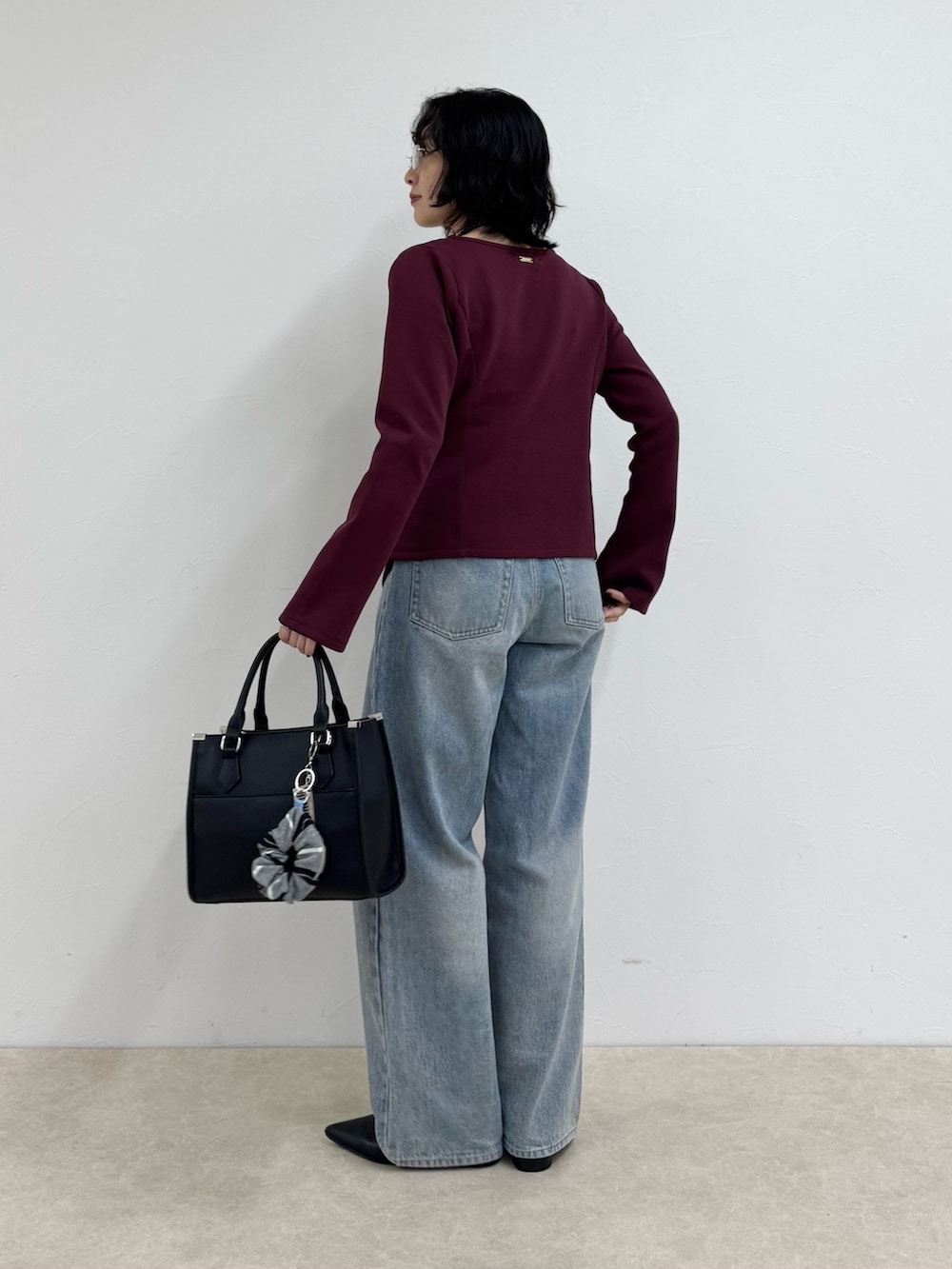 レッド系のTシャツ/カットソー、ブルー系のデニムパンツ、ブラック系のボストンバッグを着用したレディースの秋コーディネートの3枚目の写真