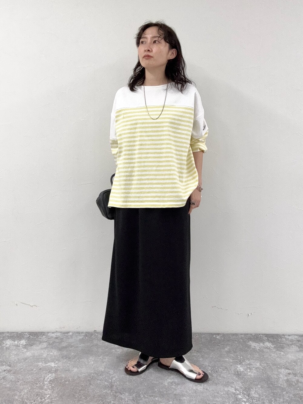 イエロー系のTシャツ/カットソー、ブラック系のスカート、ブラック系のショルダーバッグを着用したレディースの春コーディネートの2枚目の写真