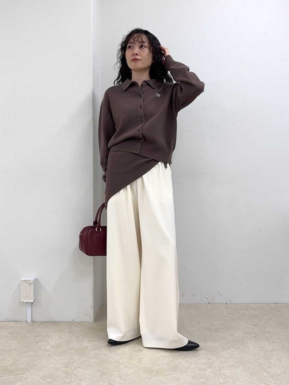 ブラウン系のニット/セーター、ホワイト系のその他パンツ、レッド系のショルダーバッグを着用したレディースの秋コーディネートの6枚目の写真