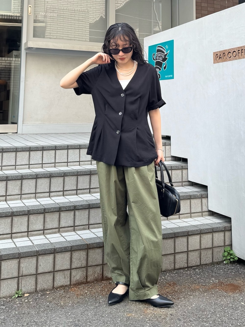 ブラック系のテーラードジャケット、グリーン系のその他パンツ、ブラック系のショルダーバッグを着用したレディースの春コーディネートの7枚目の写真