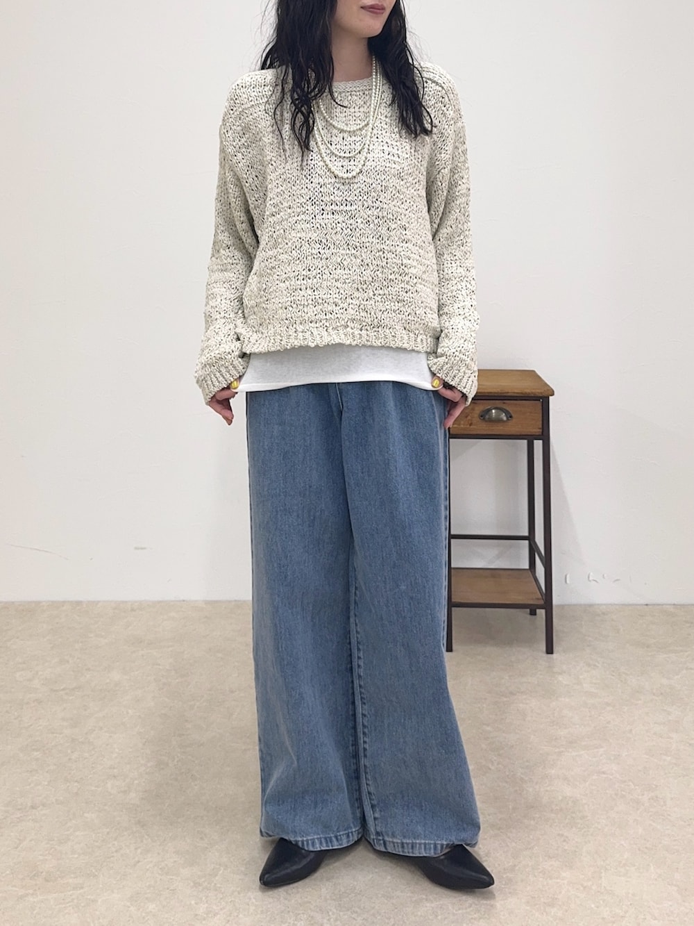 ベージュ系のニット/セーター、ホワイト系のTシャツ/カットソー、ブルー系のデニムパンツを着用したレディースの春コーディネートの2枚目の写真