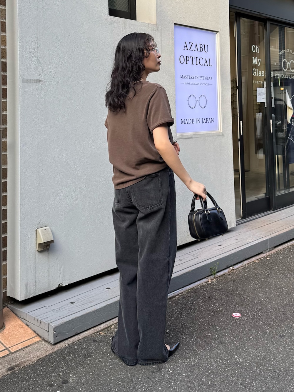 ブラウン系のTシャツ/カットソー、ブラック系のデニムパンツ、ブラック系のショルダーバッグを着用したレディースの夏コーディネートの2枚目の写真