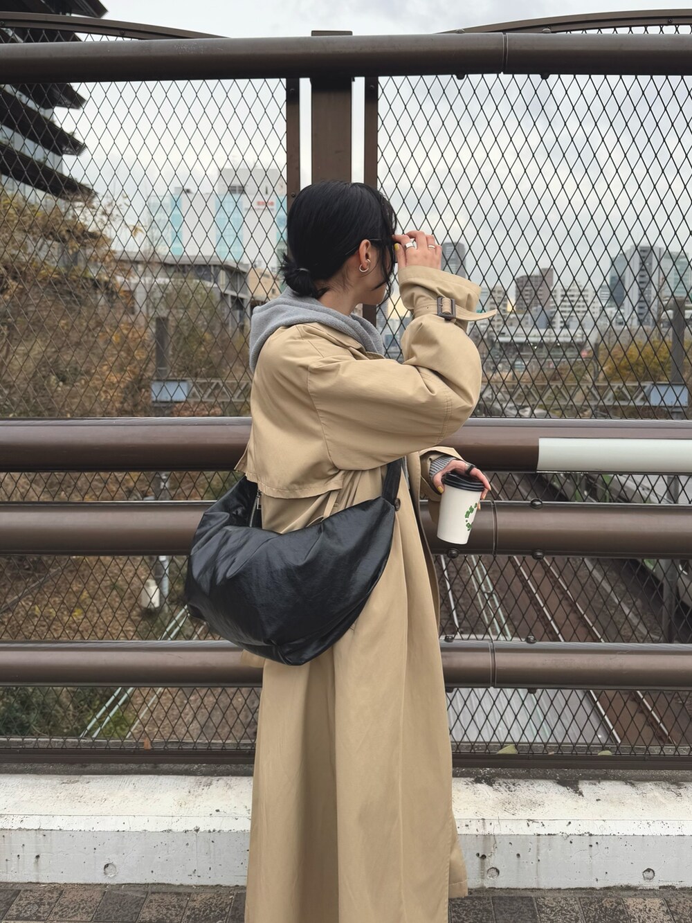 グレー系のパーカー、ベージュ系のトレンチコート、ブラック系のスカートを着用したレディースの冬コーディネートの5枚目の写真