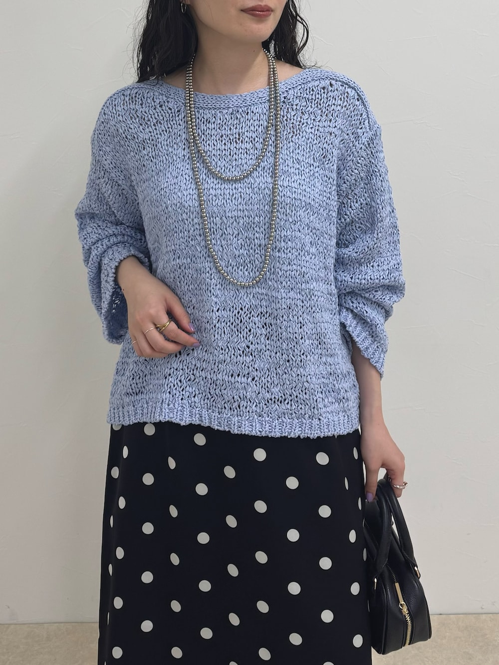 ブルー系のニット/セーター、ブラック系のスカート、ブルー系のデニムパンツを着用したレディースの春コーディネートの4枚目の写真