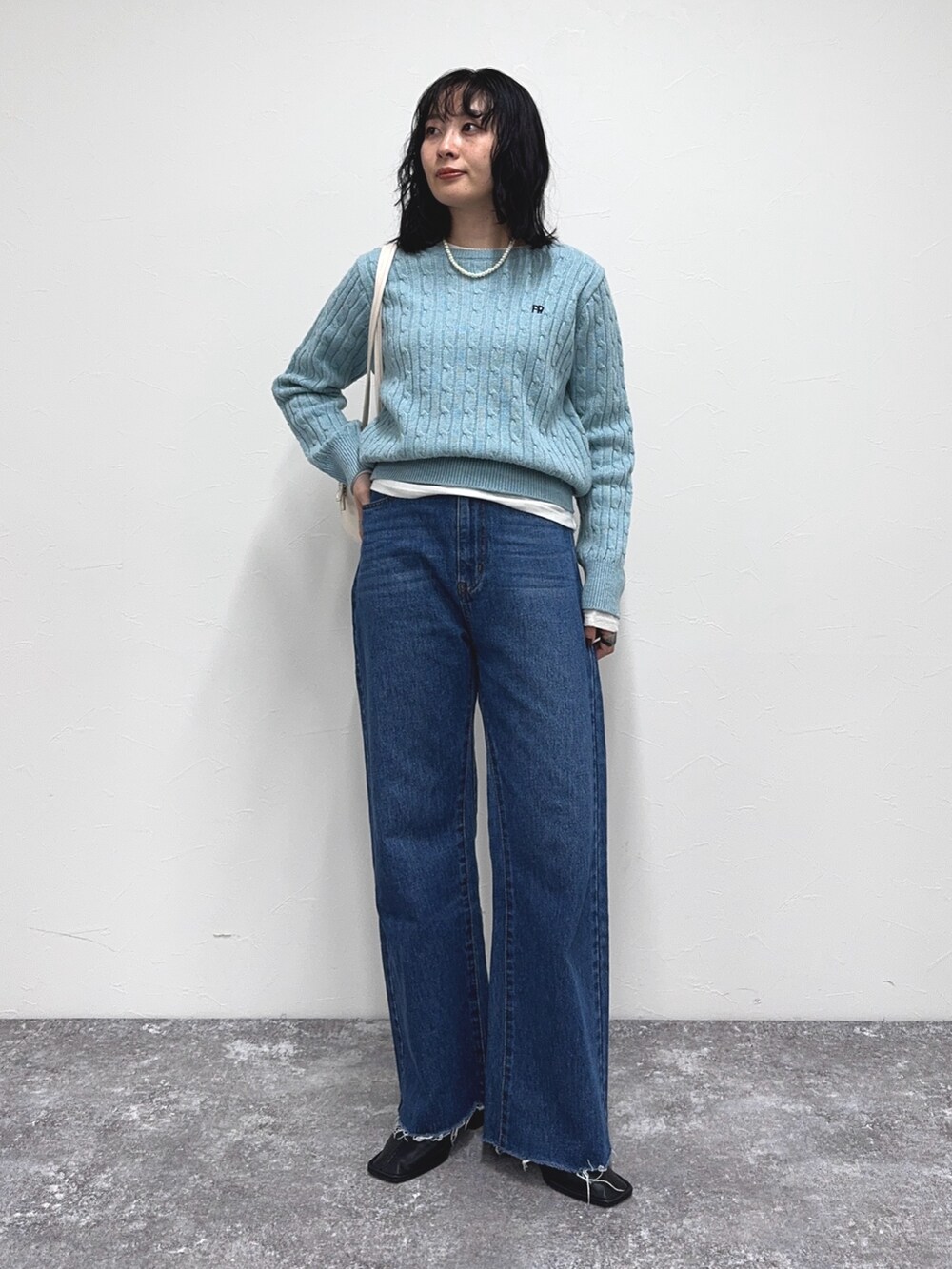 ブルー系のニット/セーター、ブルー系のデニムパンツ、ホワイト系のTシャツ/カットソーを着用したレディースの冬コーディネートの2枚目の写真