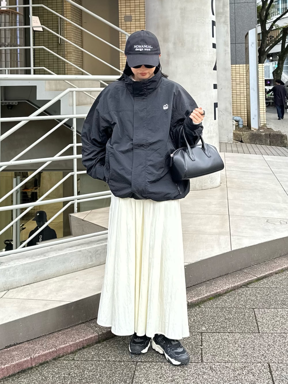 ホワイト系のスカート、グレー系のスウェット、ブラック系のマウンテンパーカーを着用したレディースの秋コーディネートの6枚目の写真