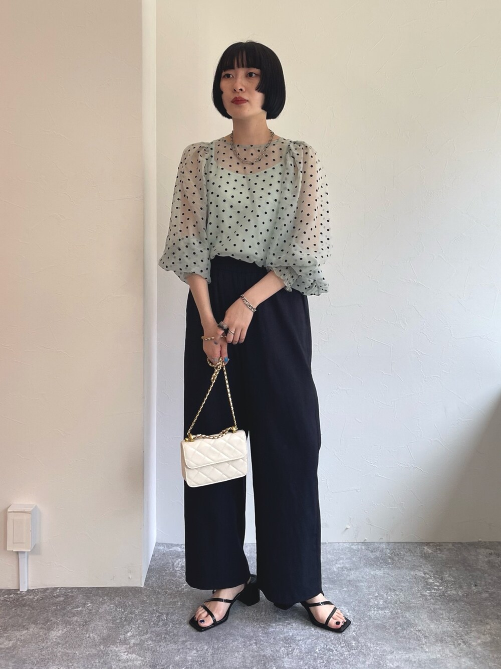 ブルー系のシャツ/ブラウス、ブラック系のスラックス、ホワイト系のショルダーバッグを着用したレディースの春コーディネートの2枚目の写真