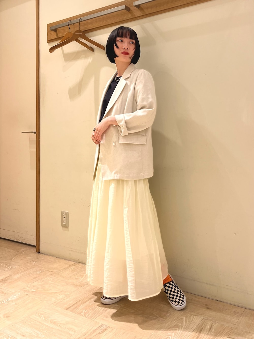 ベージュ系のテーラードジャケット、ブラック系のTシャツ/カットソー、ベージュ系のスカートを着用したレディースの春コーディネートの2枚目の写真