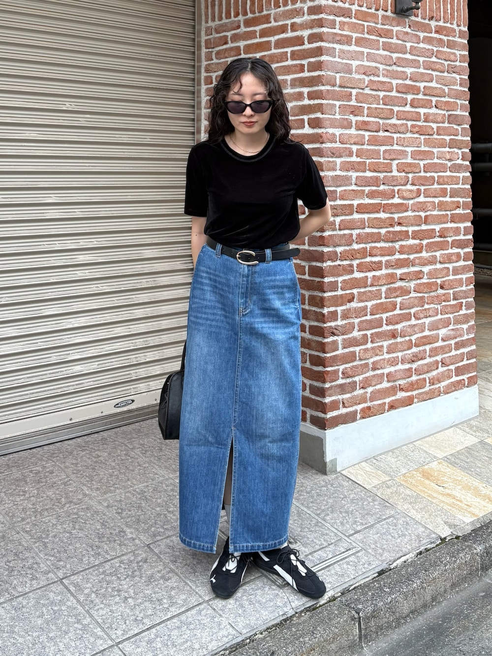 ブラック系のTシャツ/カットソー、ブルー系のデニムスカート、ブラック系のショルダーバッグを着用したレディースの夏コーディネートの7枚目の写真