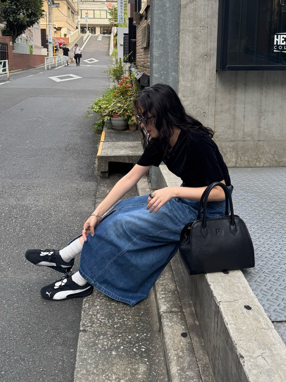 ブラック系のTシャツ/カットソー、ブルー系のデニムスカート、ブラック系のショルダーバッグを着用したレディースの夏コーディネートの8枚目の写真