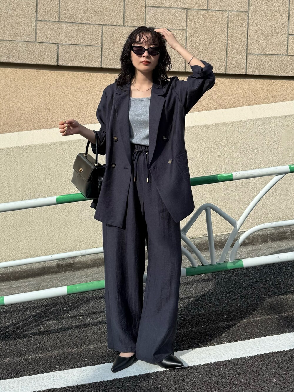 ブルー系のテーラードジャケット、ブルー系のその他パンツ、ブラック系のショルダーバッグを着用したレディースの春コーディネートの5枚目の写真