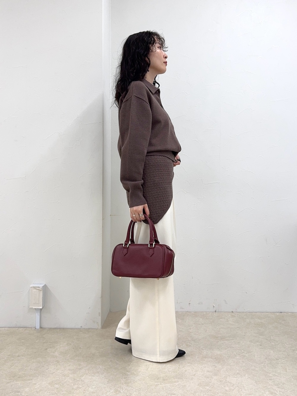 ブラウン系のニット/セーター、ホワイト系のその他パンツ、レッド系のショルダーバッグを着用したレディースの秋コーディネートの3枚目の写真