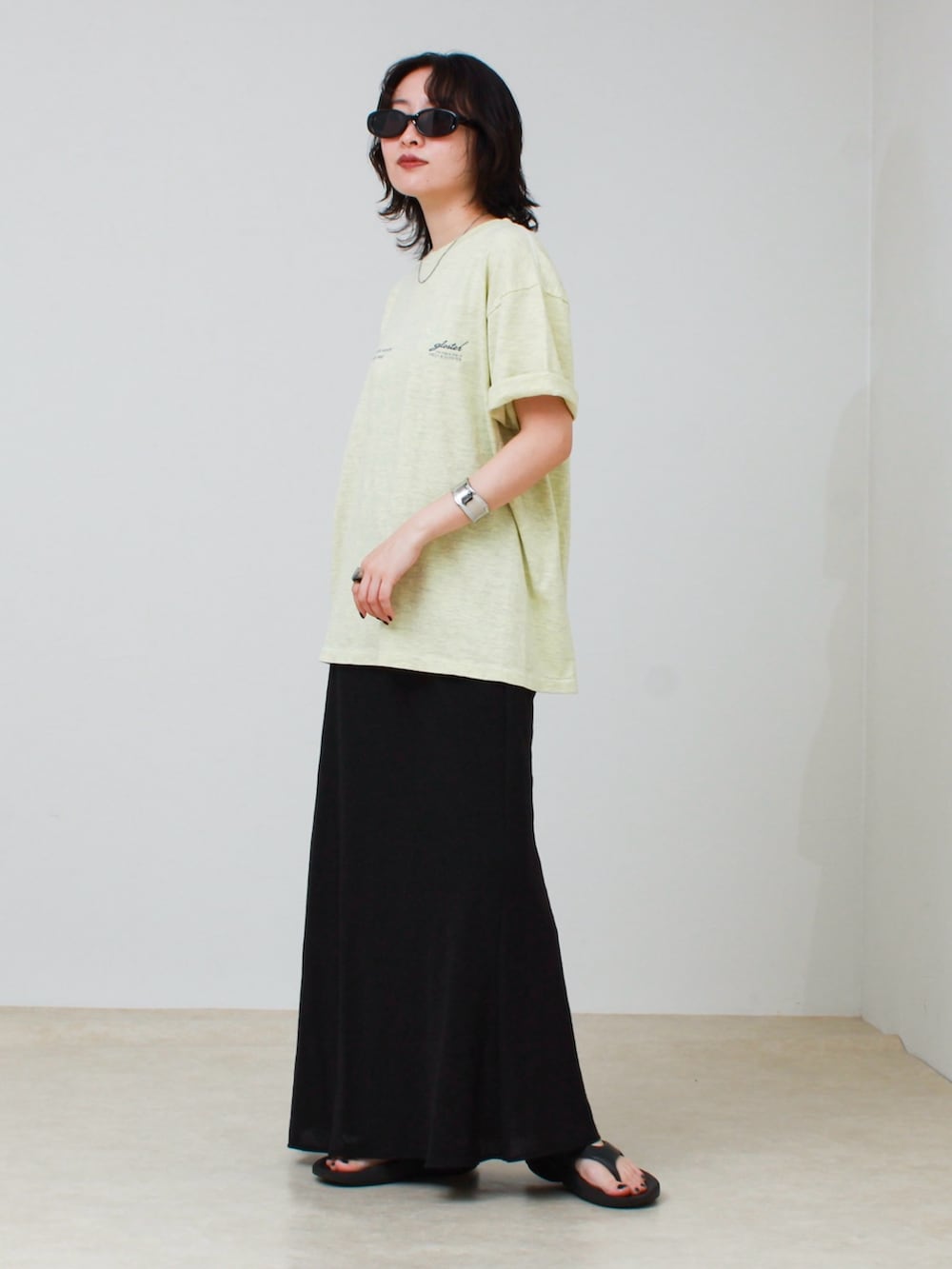 イエロー系のTシャツ/カットソー、ブラック系のスカート、ブラック系のサンダルを着用したレディースの夏コーディネートの2枚目の写真
