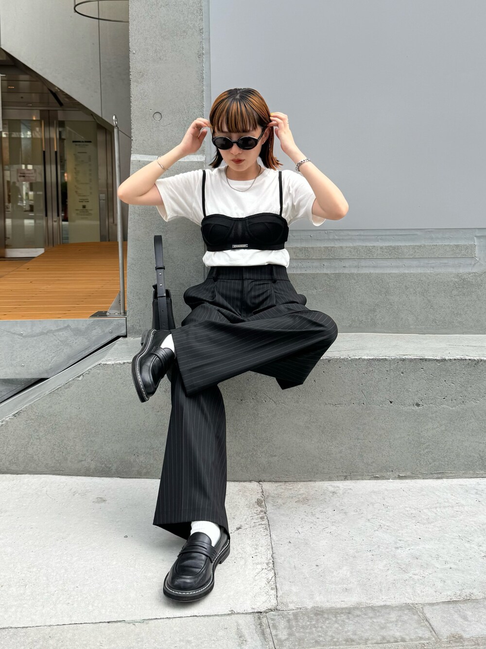 ホワイト系のTシャツ/カットソー、ブラック系のスラックス、ブラック系のハンドバッグを着用したレディースの夏コーディネートの3枚目の写真