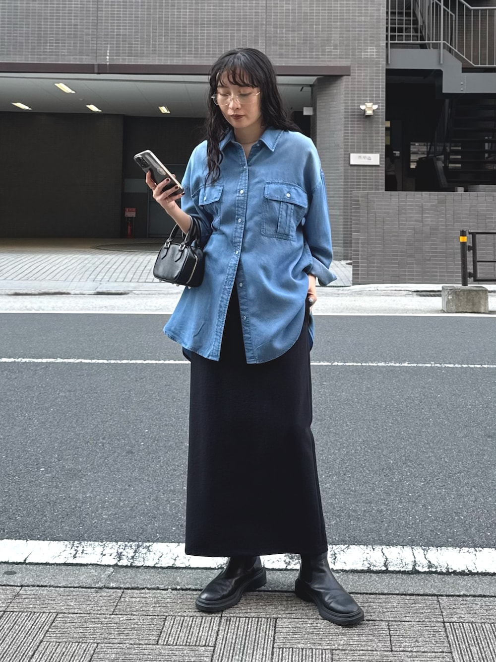 ブルー系のシャツ/ブラウス、ブラック系のスカートを着用したレディースの春コーディネートの2枚目の写真