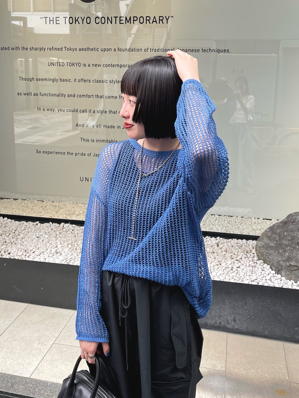 ブルー系のニット/セーター、ブラック系のカーゴパンツ、ブラック系のサンダルを着用したレディースの夏コーディネートの3枚目の写真