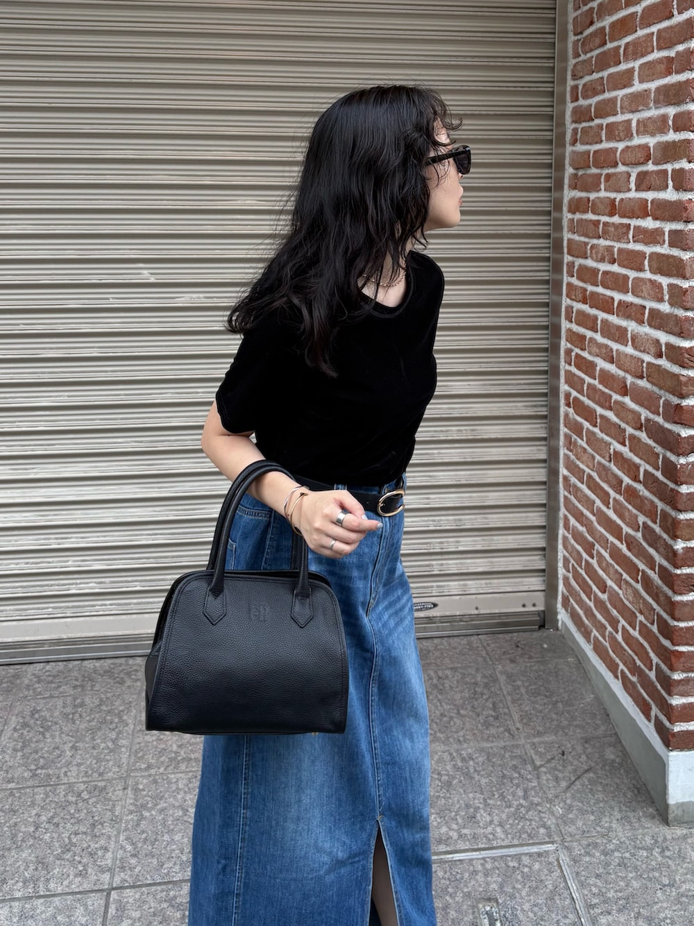 ブラック系のTシャツ/カットソー、ブルー系のデニムスカート、ブラック系のショルダーバッグを着用したレディースの夏コーディネートの6枚目の写真