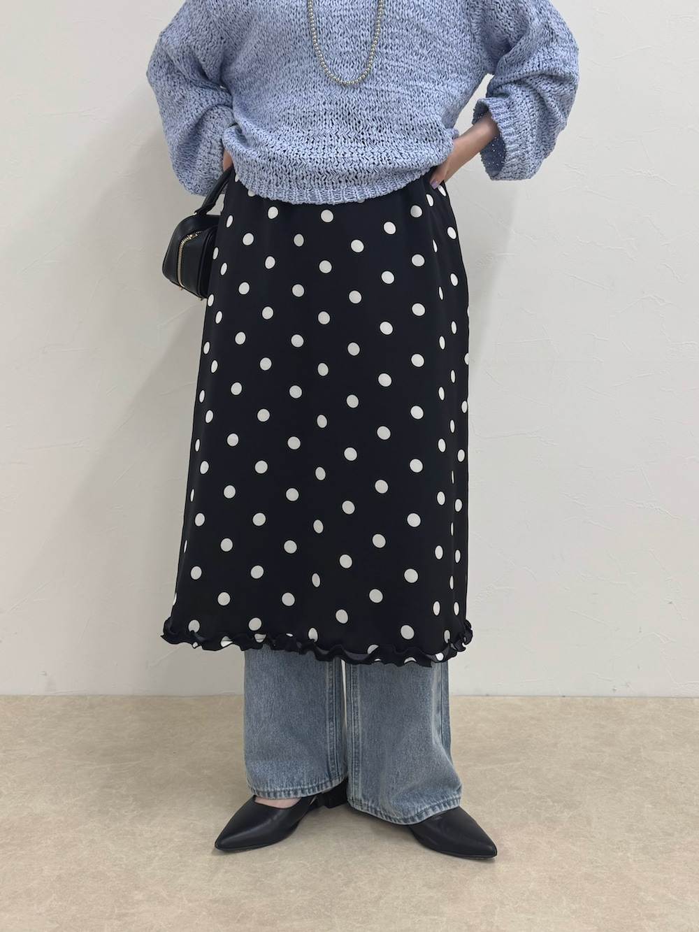 ブルー系のニット/セーター、ブラック系のスカート、ブルー系のデニムパンツを着用したレディースの春コーディネートの5枚目の写真