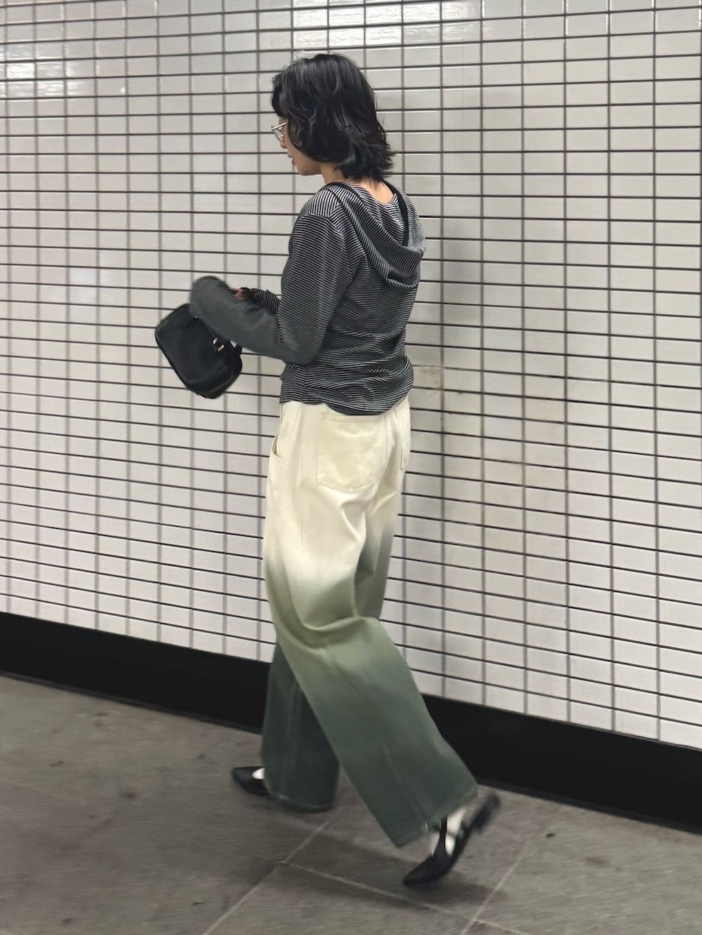 ブラック系のTシャツ/カットソー、グリーン系のデニムパンツを着用したレディースの秋コーディネートの6枚目の写真
