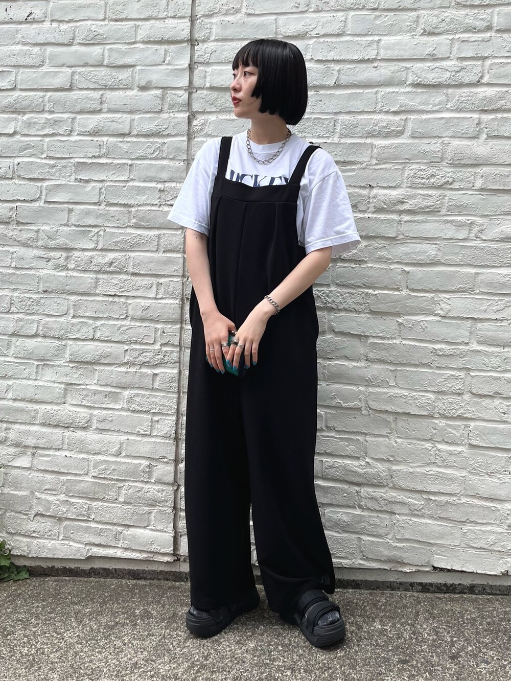 ホワイト系のTシャツ/カットソー、ブラック系のサロペット/オーバーオール、ブラック系のサンダルを着用したレディースの夏コーディネートの2枚目の写真